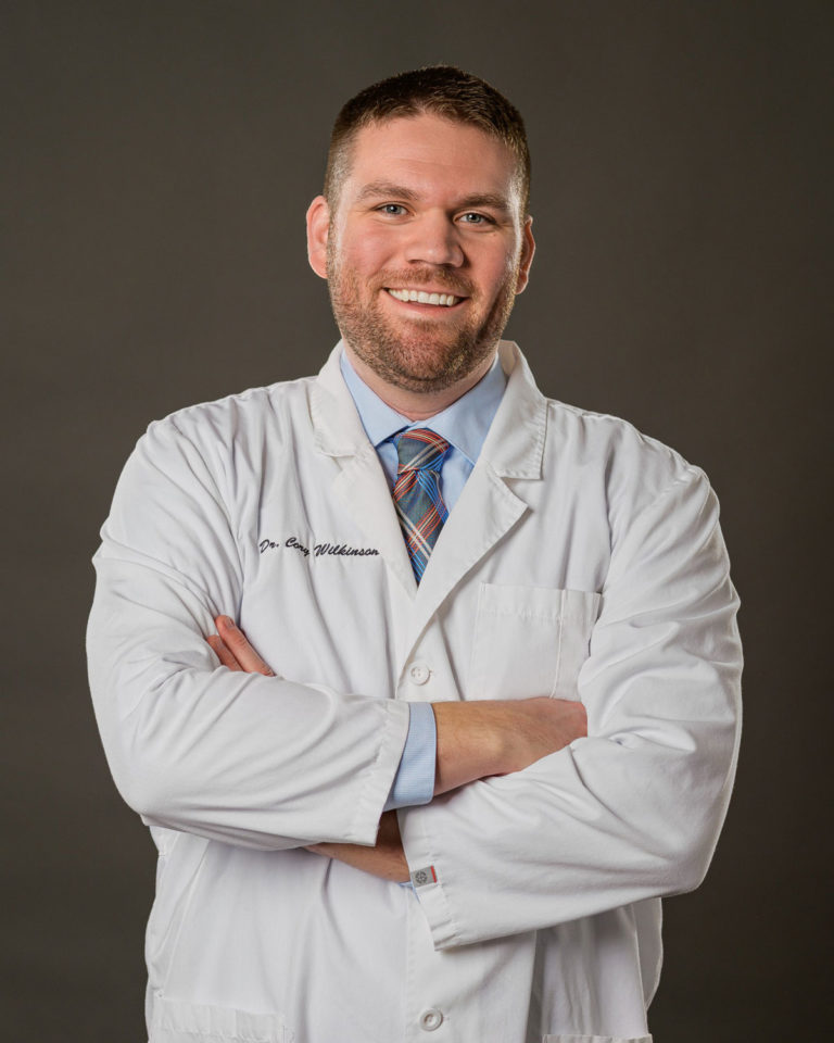 Dr. Cory Wilkinson, dentist at Healthy Smiles Family Dentistry smiling with arms crossed in dental coat