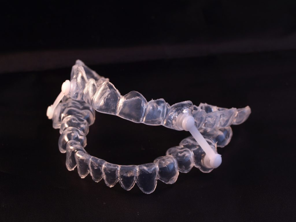 Clear oral appliance sits on a black background